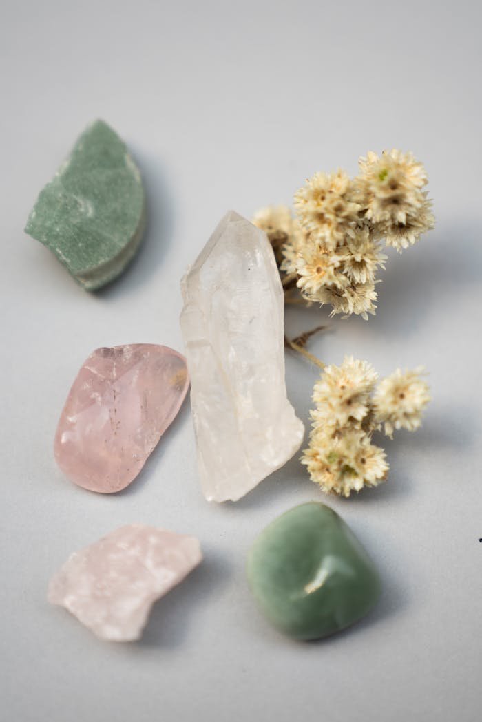 our-mission-01 Close-up of assorted healing crystals and dried flowers on a gray surface.