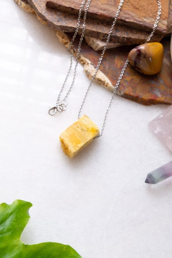 Beautiful necklace featuring a yellow gemstone pendant on a white surface with complementary crystals.